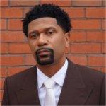 Jalen Rose in a portrait against a brick wall